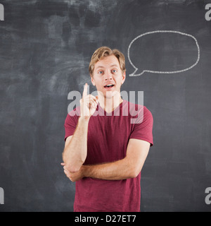 Studio shot of mid adult man with chalk drawing of speech bubble on blackboard Stock Photo