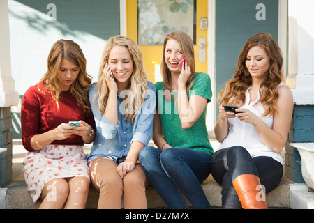 USA, Utah, Provo, Four friends sitting on porch with their mobile phones Stock Photo