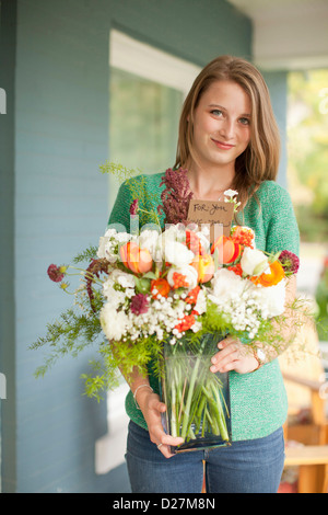 USA, Utah, Provo, Portrait of young woman holding vase with flowers Stock Photo