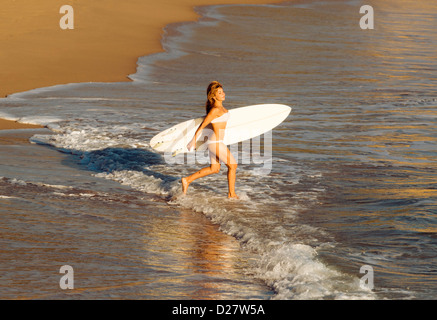 Woman going into the sea with her surf board. Stock Photo