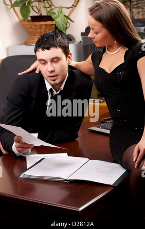 Young female assistant holding documents to sign for her chief Stock Photo