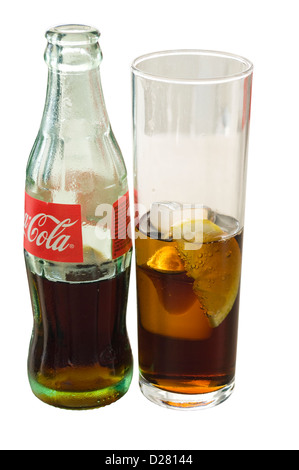 Glass Bottle Of Coca Cola next to A Glass Of Coca Cola With Ice Cubes and A Slice Of Lemon Stock Photo