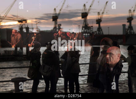 Visitors at Hamburg's fish market along the Elbe river are reflected in the window glass of the event hall in which live music is offered to the guests inside the hall. Stock Photo