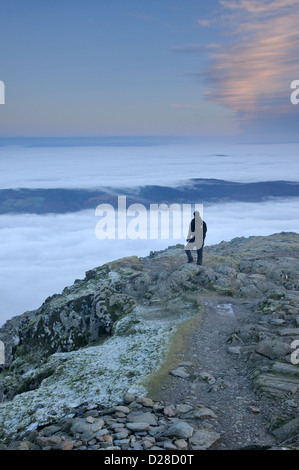 Lone walker on the summit of the Old Man of Coniston above a temperature inversion in the English Lake District Stock Photo