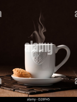 Cup of steaming coffee with biscuits on wooden table Stock Photo