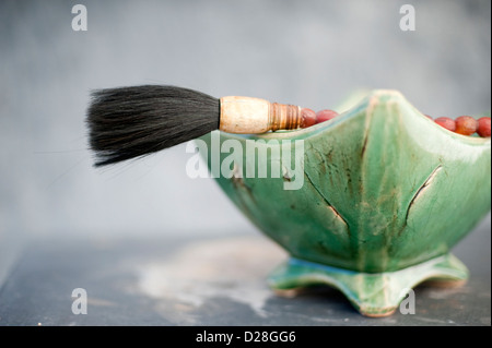 Still life of a traditional Chinese calligraphy brush propped on a bowl of stones. Stock Photo