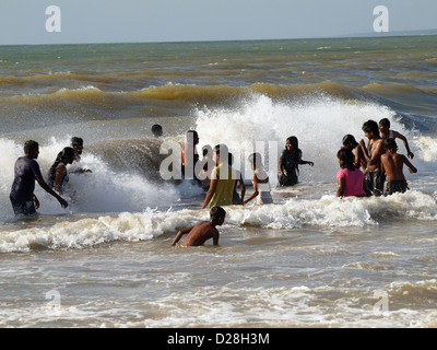 local people at Negombo Sri lanka enjoy the surf and crashing waves in the sea in the evening Stock Photo