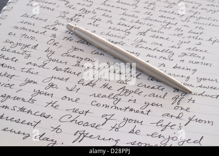 A Stainless Steel Ball Point Pen is Laying on the Written Page of a Spiral Bound Notebook Stock Photo