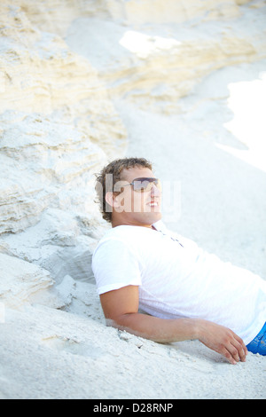 Young man relaxing on white sand of exotic beach Stock Photo