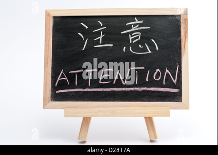 Bilingual word of Attention in both Chinese and English written on blackboard over white background Stock Photo