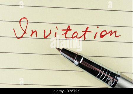 Invitation word written on lined paper with a pen on it Stock Photo