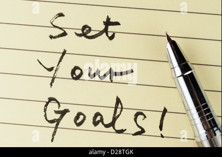 Set your goals words written on lined paper with a pen on it Stock Photo