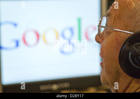 Computer class for people with visual impairments - man using headphones for audio, Google on the computer screen. Stock Photo