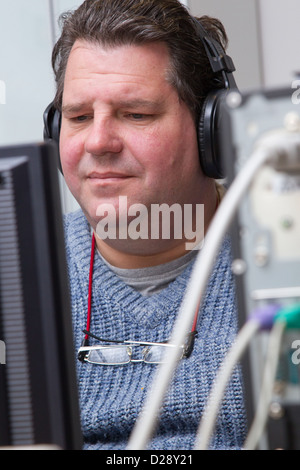 Computer class for people with visual impairments - man using headphones for audio. Stock Photo