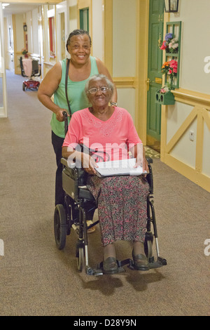 Carer pushing elderly visually impaired woman Stock Photo