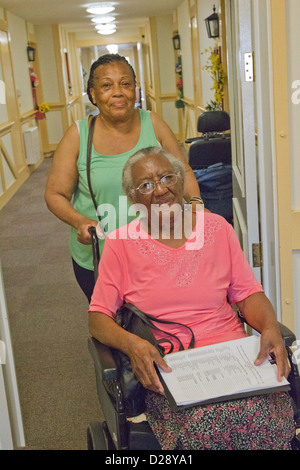Carer pushing elderly visually impaired woman Stock Photo