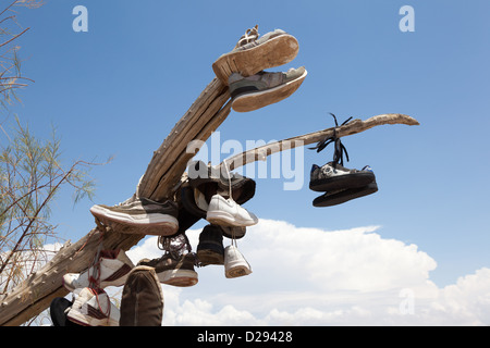 Shoes hanging from a dried branch that forms part of a shoe fence on CA 62 near Rice west of Vidal Junction, California USA Stock Photo