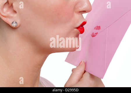 Woman wearing red lipstick kissing an envelope - Sealed With A Loving Kiss or SWALK for short. Stock Photo