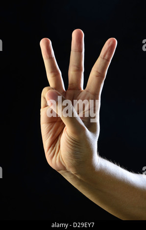 Hand showing three fingers on black background, closeup. Sign language Stock Photo