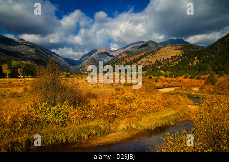 The peaks of the Colorado Rockies are framed by the brilliant sky and golden Autumn landscape as the river cuts through Stock Photo