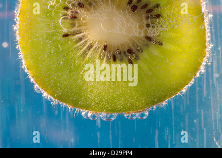 A slice of Kiwi fruit in a glass of sparkling mineral water Stock Photo