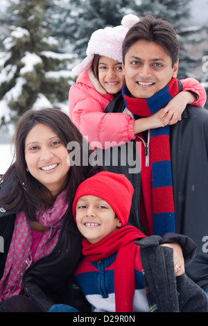 A beautiful East Indian parents play with her children in the snow. Stock Photo