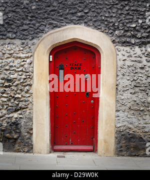 Ancient wooden door in a stone wall, painted red and with the words Stage Door Stock Photo