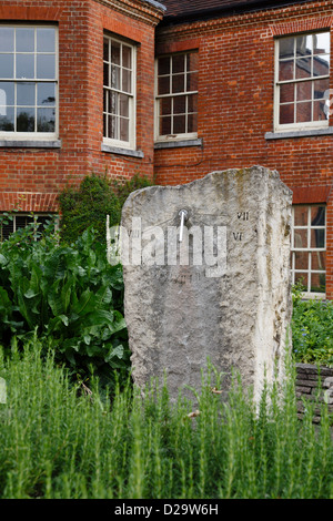 Stone sun dial in Abbey Gardens with Abbey House in the background. Winchester, Hampshire, UK Stock Photo