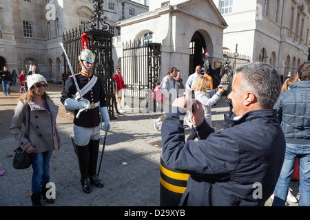 Woman tourist poses for a photograph alongside a soldier of the 'Blues and Royals' Household Cavalry in Horseguards Parade. Stock Photo