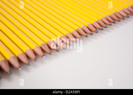 Several yellow, number 2 pencils with sharpened tips, lined up in a row on white. Stock Photo