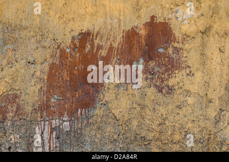 Old yellow grunge painted wall with brown spots Stock Photo