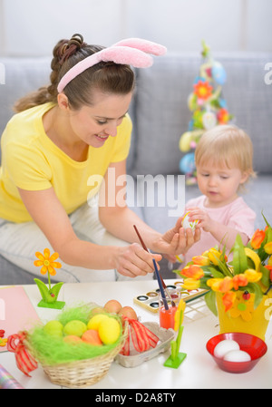 Happy mother and baby painting on Easter eggs Stock Photo