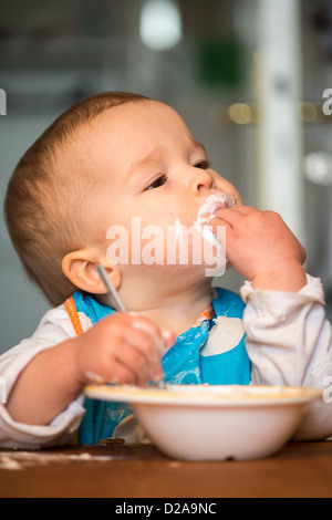 Berlin, Germany, a toddler with Schnute eating yogurt with their hands Stock Photo