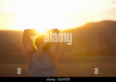 Man stretching in field at sunset Stock Photo