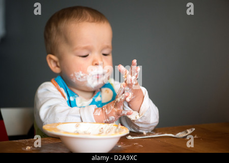 Berlin, Germany, a toddler with Schnute eating yogurt with their hands Stock Photo