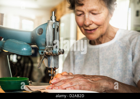 Older woman working on sewing machine Stock Photo