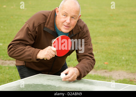 Older man playing ping pong outdoors Stock Photo