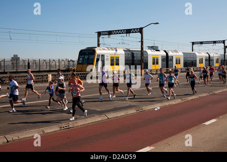 Fitness enthusiasts running across the Sydney Harbour Bridge with the suburban CityRail train in the background Stock Photo