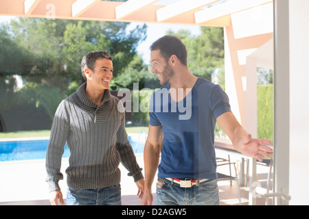 Men opening glass door in backyard Stock Photo