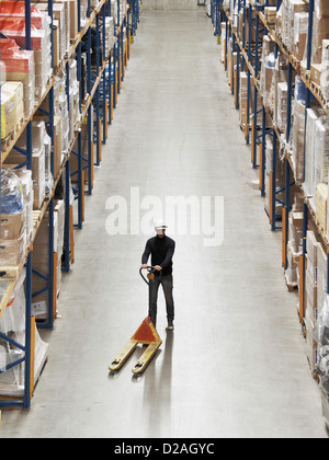 Worker operating dolly in warehouse Stock Photo