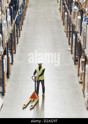 Worker operating dolly in warehouse Stock Photo