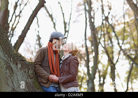 Couple leaning against tree in forest Stock Photo