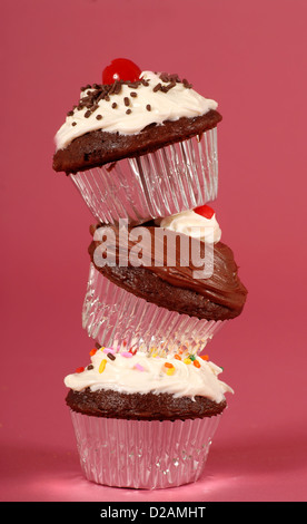 Three delicious chocolate cupcakes with buttercream frosting stacked on their edges Stock Photo