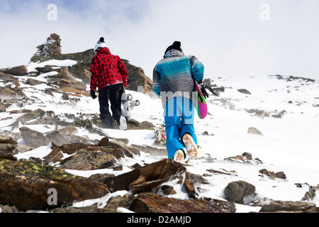 Snowboarders hiking on rocky slope Stock Photo