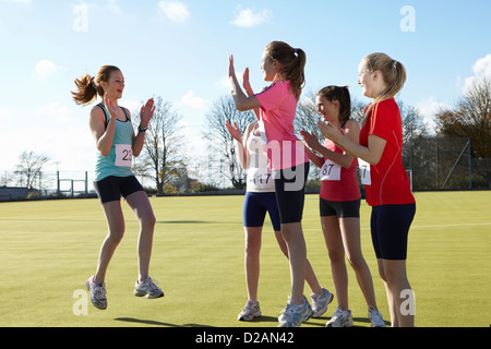 Runners cheering together in field Stock Photo