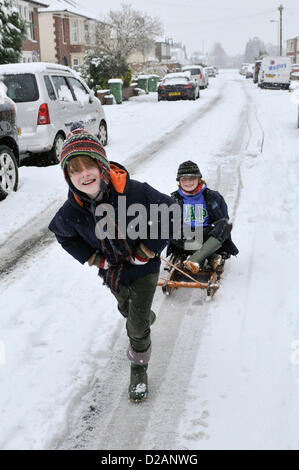 Cardiff, UK. Friday 18th January 2013. Two young boys make the best of the snow on their sledge in Cardiff, UK. All Schools  in Cardiff where closed today after heavy snow fall overnight that is to continue into the weekend. The UK Met Office has issued a severe weather warning for South East Wales. Stock Photo