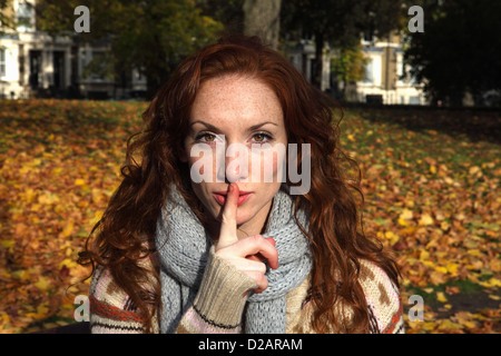 Woman holding finger over lips in park