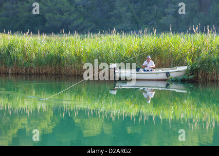 KRKA, CROATIA - JULY 28, 2012: A man fishing from a boat on July 28, 2012 in Krka, Croatia. Stock Photo