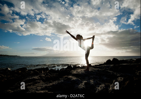 Woman practicing yoga on rock formation Stock Photo