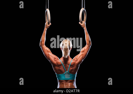 Exercising woman holding gymnast rings. Female taking rest after